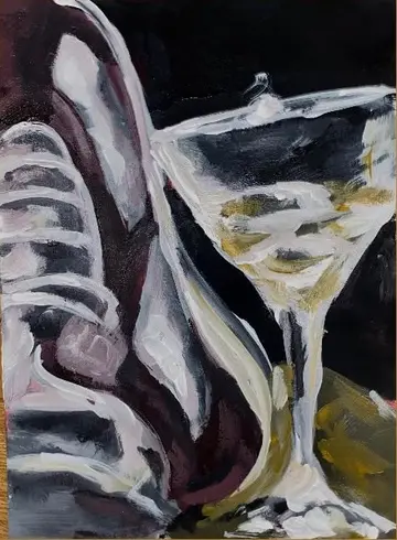 Stillleben mit einem Sneaker und einem gefüllten Cocktailglas vor dunklem Grund.